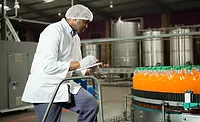 Worker checking bottles in a juice factory