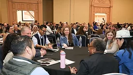 food safety summit attendees having a discussion at a round table in a crowded room