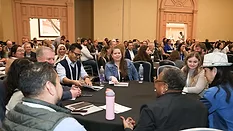 food safety summit attendees having a discussion at a round table in a crowded room