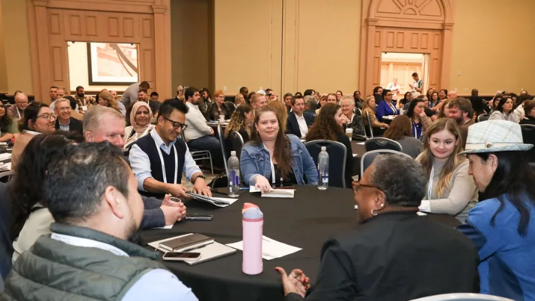 food safety summit attendees having a discussion at a round table in a crowded room