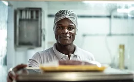 man working in food manufacturing facility wearing hairnet looking at camera with a small smile