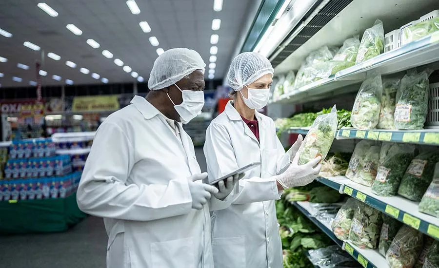 epidemiologists or scientists in white lab coats and masks and hairnets in a grocery store investigating lettuce