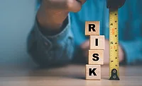 measuring risk_Dilok KlaisataporniStockGetty Images Plus via Getty Images.jpg person holding tape measure next to stack of block letters that say R I S K. measuring risk concept