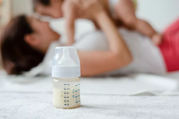 Baby formula with mother and infant in background