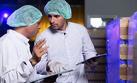 two food manufacturing personnel discussing something on a checklist clipboard