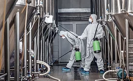 workers in protective gear performing industrial cleaning and disinfection