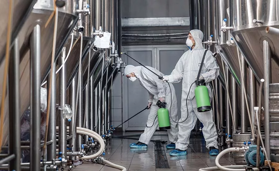 workers in protective gear performing industrial cleaning and disinfection