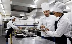 chefs in a professional kitchen setting, appearing to be discussing or reviewing something on a digital tablet. chefs in a professional kitchen setting, appearing to be discussing or reviewing something on a digital tablet.