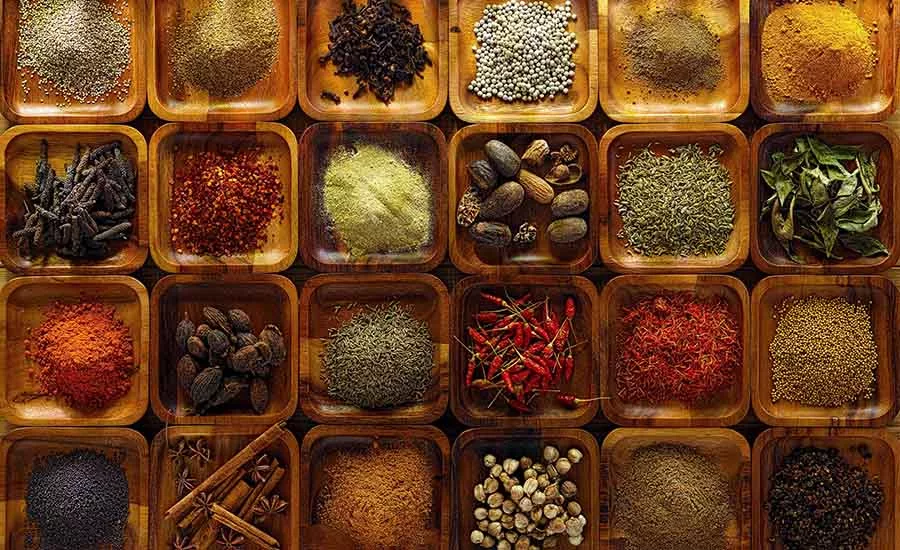 The image displays a variety of whole and ground spices, commonly used in Indian cuisine