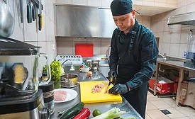 The image shows a person working on food preparation, likely in a commercial kitchen setting.