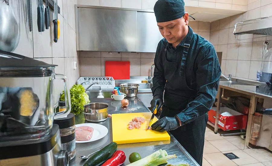 The image shows a person working on food preparation, likely in a commercial kitchen setting.