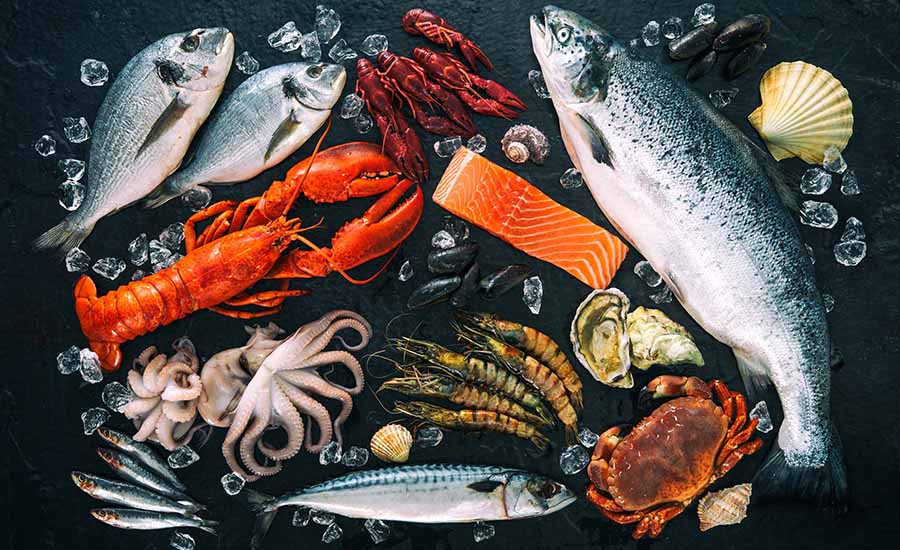 This image displays a variety of fresh seafood items, including whole salmon, lobster, octopus, shrimp, and various types of fish, arranged on a bed of ice. 
