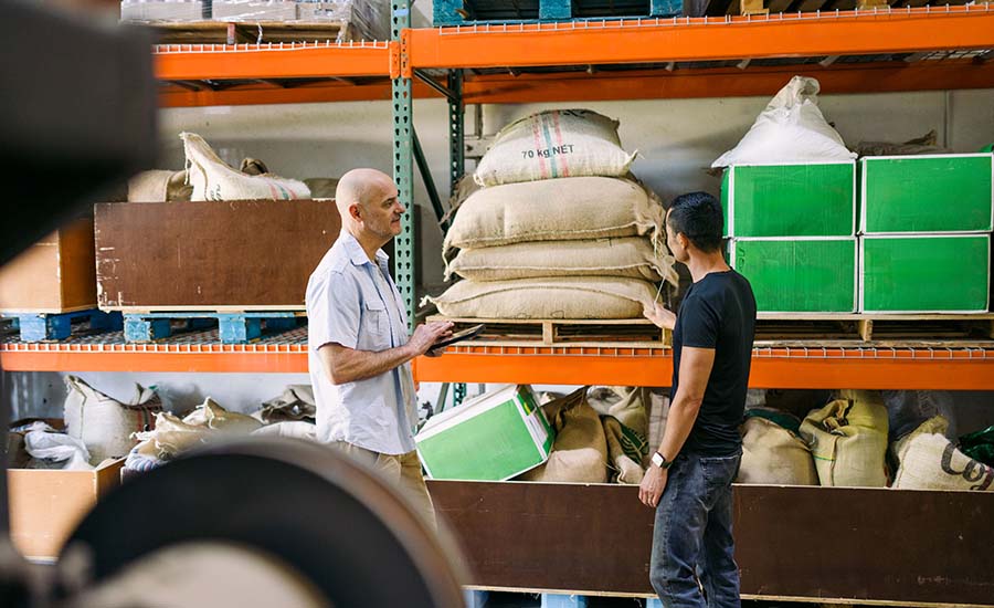 The image depicts two men in a warehouse setting