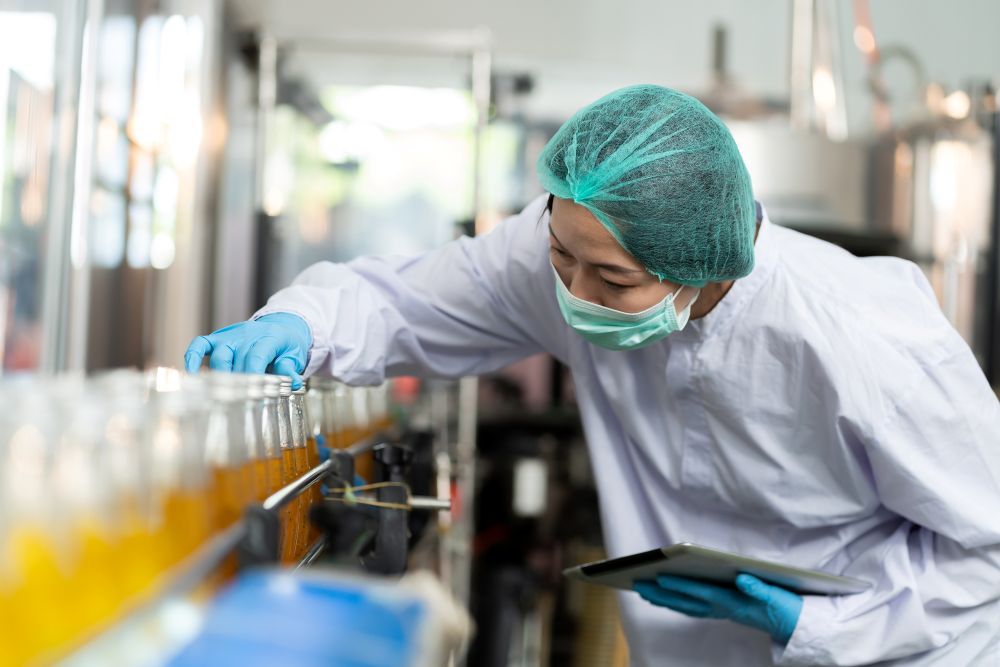a quality control worker inspecting bottled juice on a production line in a manufacturing facility