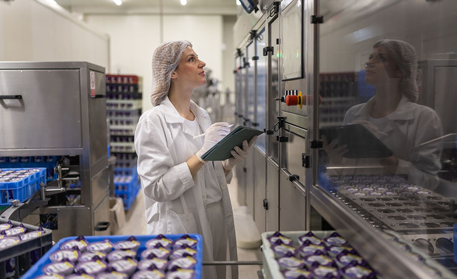 a technician in a food production facility inspecting machinery and taking notes