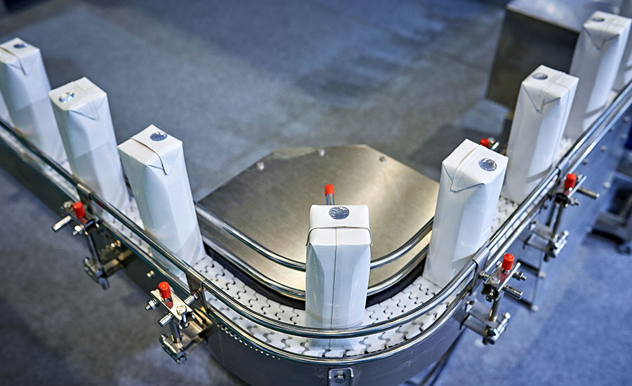blank milk or juice cartons moving along an automated factory conveyor belt