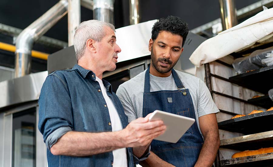  two individuals collaboratively reviewing information on a tablet within a professional kitchen environment