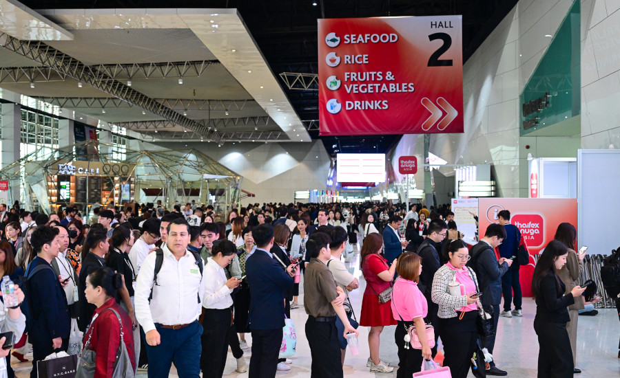 a crowd of people walking through a brightly lit hall at the THAIFEX - Anuga Asia 2026 trade show in Bangkok