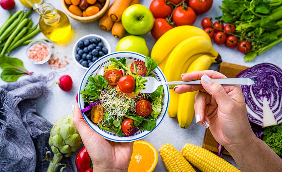 Woman eating fresh rainbow colored salad