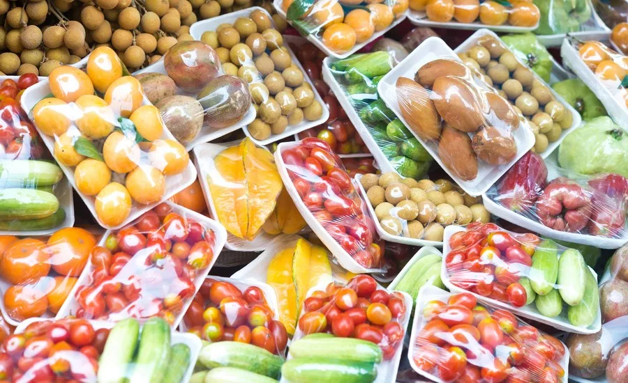 The image shows a variety of fresh produce packaged in plastic trays and wrap.