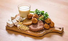 This image features a variety of plant-based meat alternative products, including tofu, plant-based milk, and veggie patties or meatballs. 