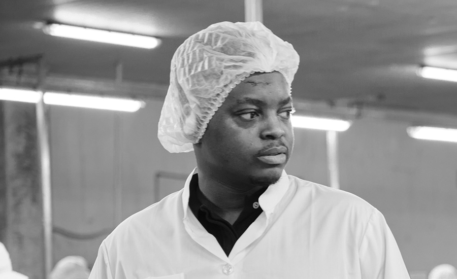an individual wearing a white hairnet and a white collared work shirt, commonly seen in a food processing or manufacturing environment