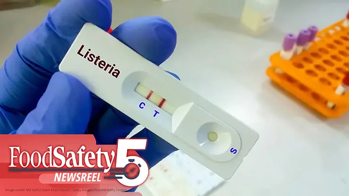 a person wearing blue gloves holding a rapid test cassette labeled "Listeria" with two red lines visible in the control (C) and test (T) zones a person wearing blue gloves holding a rapid test cassette labeled "Listeria" with two red lines visible in the control (C) and test (T) zones