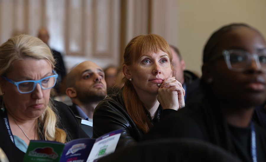 an audience sitting in rows during a conference or seminar event, with attendees listening to a presentation