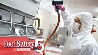 a sanitation worker in protective gear using a high-pressure washdown hose to clean industrial food processing equipment a sanitation worker in protective gear using a high-pressure washdown hose to clean industrial food processing equipment