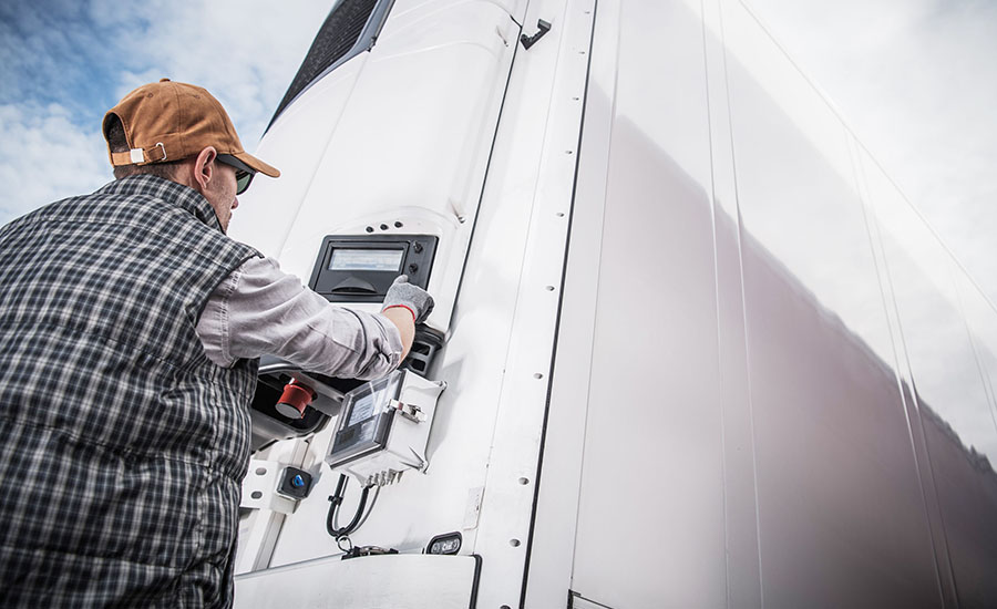 a truck driver adjusting the digital control panel of a refrigerated semi-trailer unit (reefer)