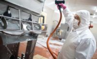 employee cleans food processing equipment