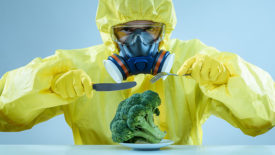 man in a hazmat suit eating broccoli