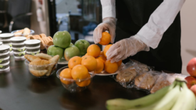 food handler wearing gloves holding fruit