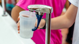 child filling drinking cup with tap water