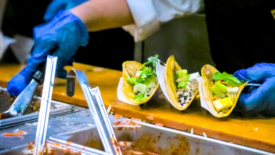 gloved employee prepares tacos