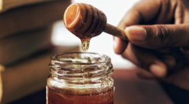 hand dipping wand into honey jar