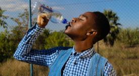 man outdoors drinking from plastic water bottle