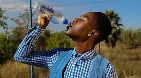 man outdoors drinking from plastic water bottle
