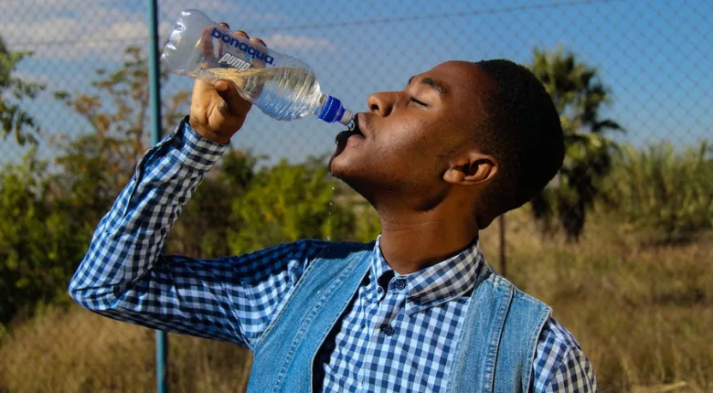 man outdoors drinking from plastic water bottle