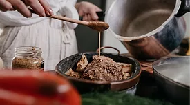 person drizzling sauce on meat