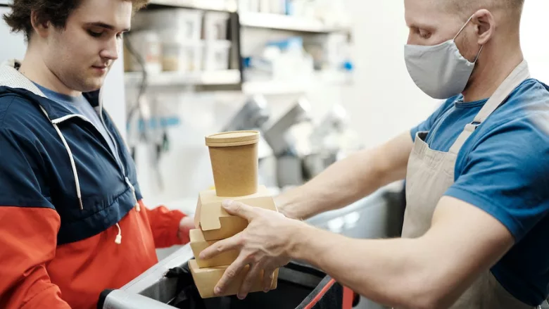person handing food to delivery courier