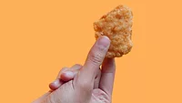 person holding chicken nugget yellow background.png person holding a chicken nugget against a yellow background