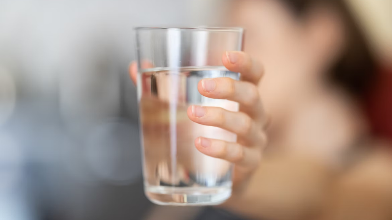 person holding up glass of water