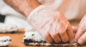 person rolling sushi wearing disposable gloves