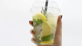person's hand holding plastic cup of lemonade