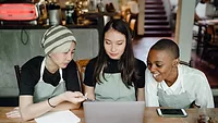 three waitresses working on a laptop in a cafe.png three waitresses working on a laptop in a cafe