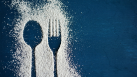 white powder on a blue surface arranged to make the silhouettes of a fork and spoon