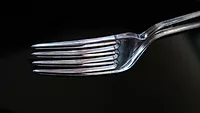 clear plastic fork against black background