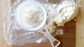 flour in sifter on wooden board