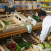 grocer bent over fixing vegetable display